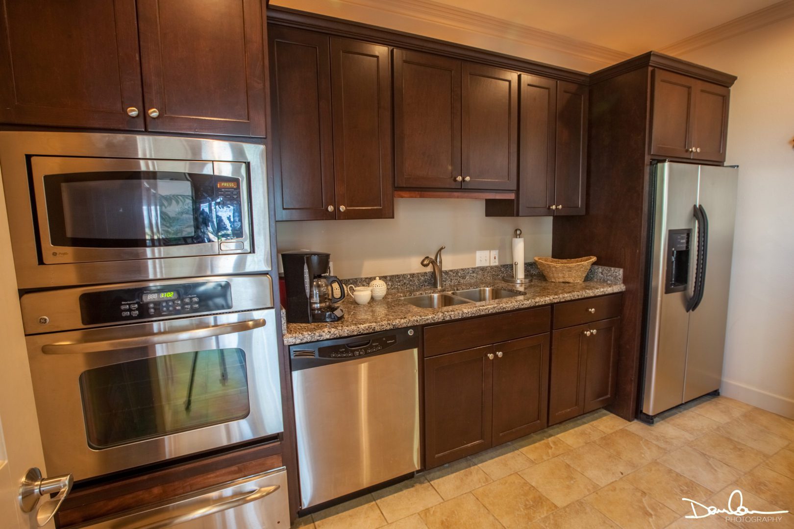 A small kitchen with a refrigerator, oven, and microwave